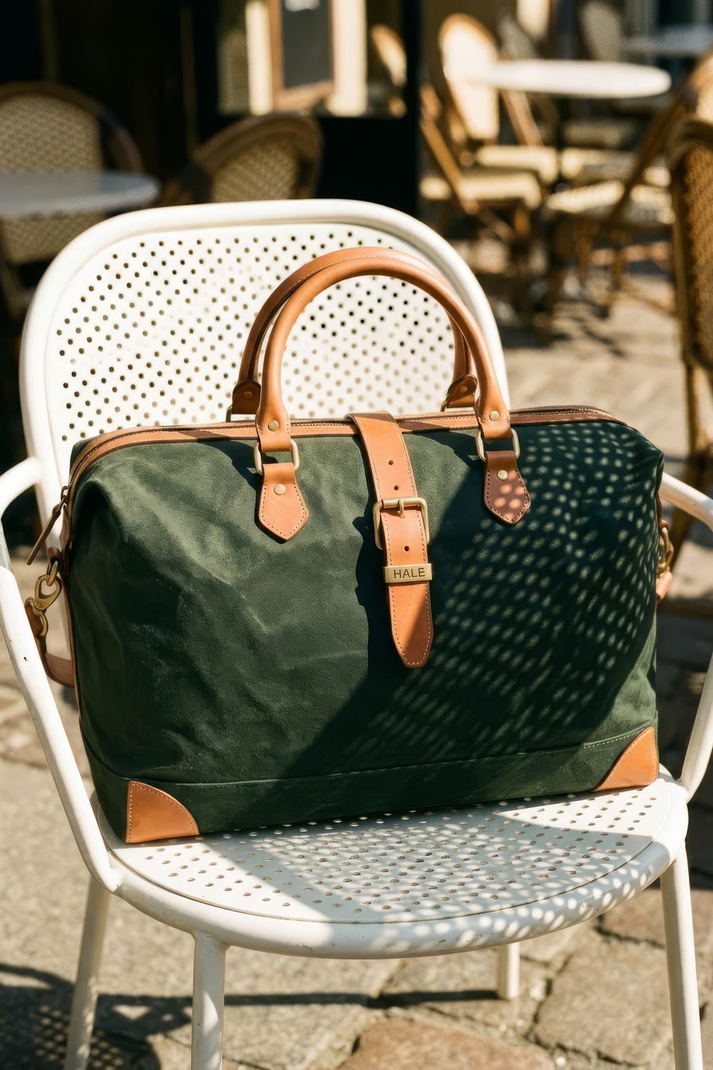 The holdall on a white perforated bistro chair with a dotted shadow across it