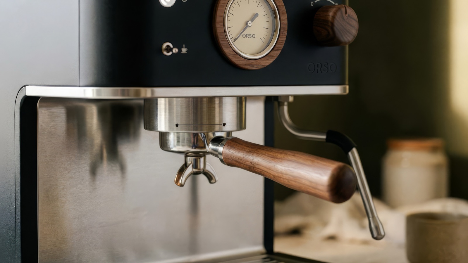 Close-up of the brushed steel group head, walnut portafilter handle and steam wand