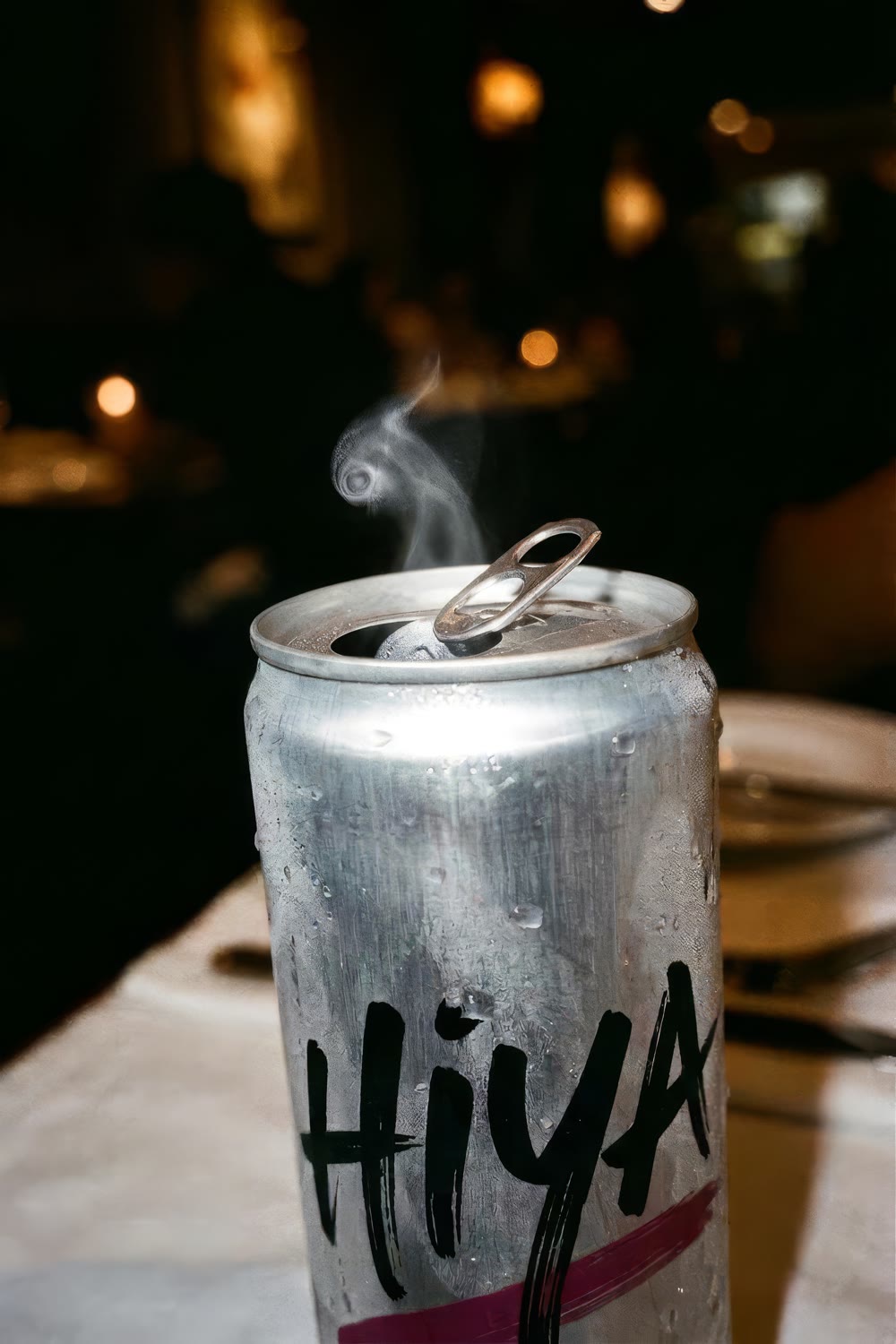 A freshly opened can with the tab up and a curl of cold mist rising from the mouth